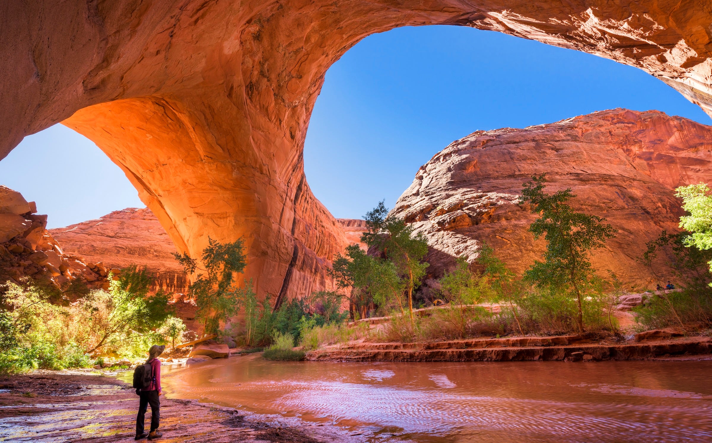 A hiker at Jacob Hamblin Arch in Coyote Gulch, Grand Staircase-Escalante National Monument, Utah, United States to demonstrate the solitary way