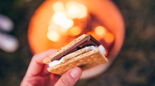 person holding a s'more over a campfire
