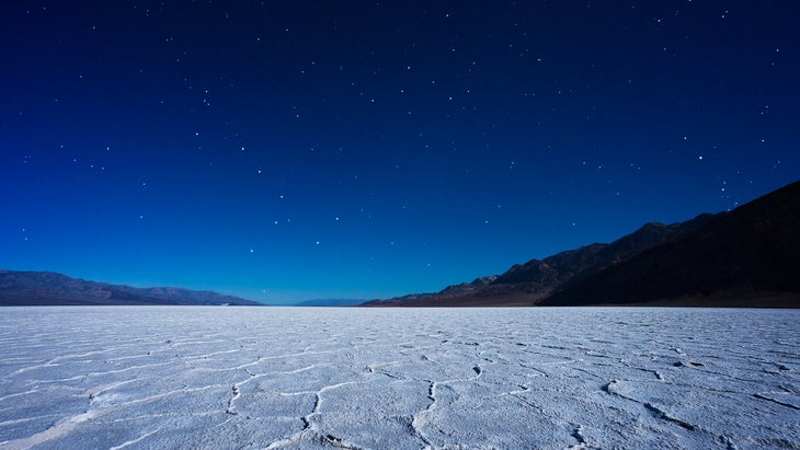 Badwater Basin in Death Valley National Park under starry skies and lit by a full moon.
