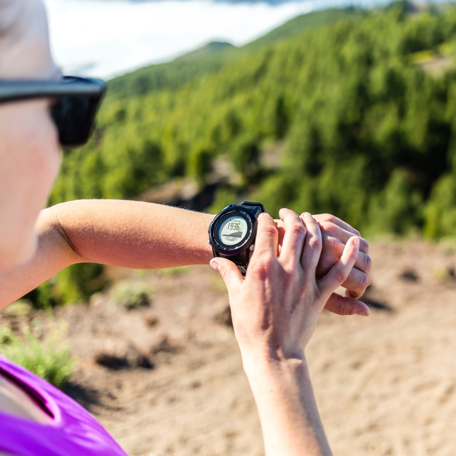 Trail runner or hiker on mountain path looking at sportwatch, checking performance or heart pulse. Cross country running in beautiful nature, Canary Islands. Sport and exercising outdoors