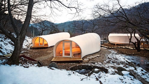 A pleasing combination of natural surroundings and glamorous internal amenities make these South Korean accommodations ideal for the less rustically inclined. The recyclable, durable units are mobile, so as to minimally impact the surrounding productive landscape. Filled with contemporary color schemes, furniture, and accessories, the units become translucent lanterns after dark.