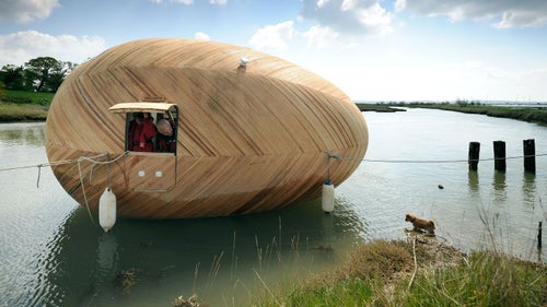 The interior of the floating wooden egg, which resides on England's Beaulieu River, is subdivided into a sleeping area with a circular skylight, a separate cooking area, and a washing area. Two plywood structures beneath the waterline allow the egg to rest on the mud below during low tide.