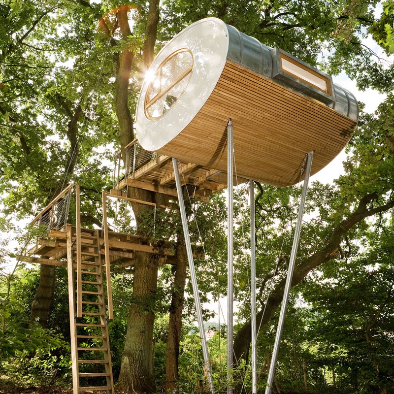 The rounded shape of the tree house calls to mind an egg sliced longitudinally. The bulk of the exterior is indigenous oak; the roof is made of zinc. The weight of this tree house is held by the trees and supports, while the weight of the terraces and the horizontal load of the tree house are distributed across the oaks by steel cables and textile straps.