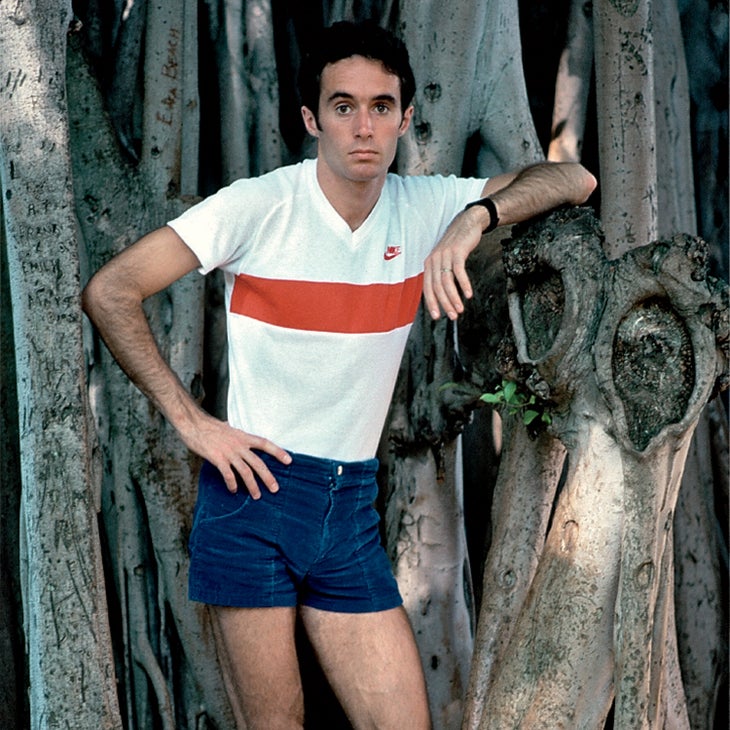 Alberto Salazar posing against a tree in shorts and a T-shirt