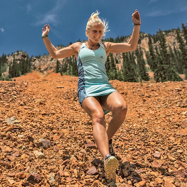 Anna Frost, another victim of overtraining syndrome, running down a rocky mountain in a blue dress