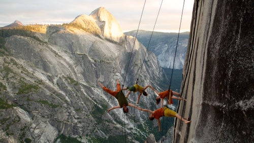 In 1989, choreographer Amelia Rudolph was clinging to a sheer granite wall in California鈥檚 Sierra Nevada when she wondered what it would look like to dance there. Soon after, Rudolph founded Bandaloop, a dance group that has performed on numerous rock walls, as well as Seattle鈥檚 Space Needle, skyscrapers in South Korea, and dozens of other sideways stages, sometimes for public audiences numbering in the tens of thousands. Beginning this June 16, six dancers and a nine-person support crew headed into Yosemite鈥檚 wilderness for ten days of hiking and pirouetting. The pinnacle of the journey was a performance on the face of 8,500-foot Mount Watkins, a stage that offers a rare perspective of Half Dome and an audience of birds, bugs, squirrels, and perhaps a bear or two.
Photo: Bandaloop dancers on Mount Watkins, nearly 3,000 feet above the valley floor. Rudolph鈥檚 goal with the group has been to challenge preconceptions about modern dance. The performers make it look easy to fly off the wall, but their abdominal muscles are often screaming as they fight gravity to hold their bodies perpendicular to the face.
