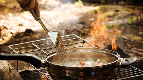 cooking a pan of bacon over a grill outside