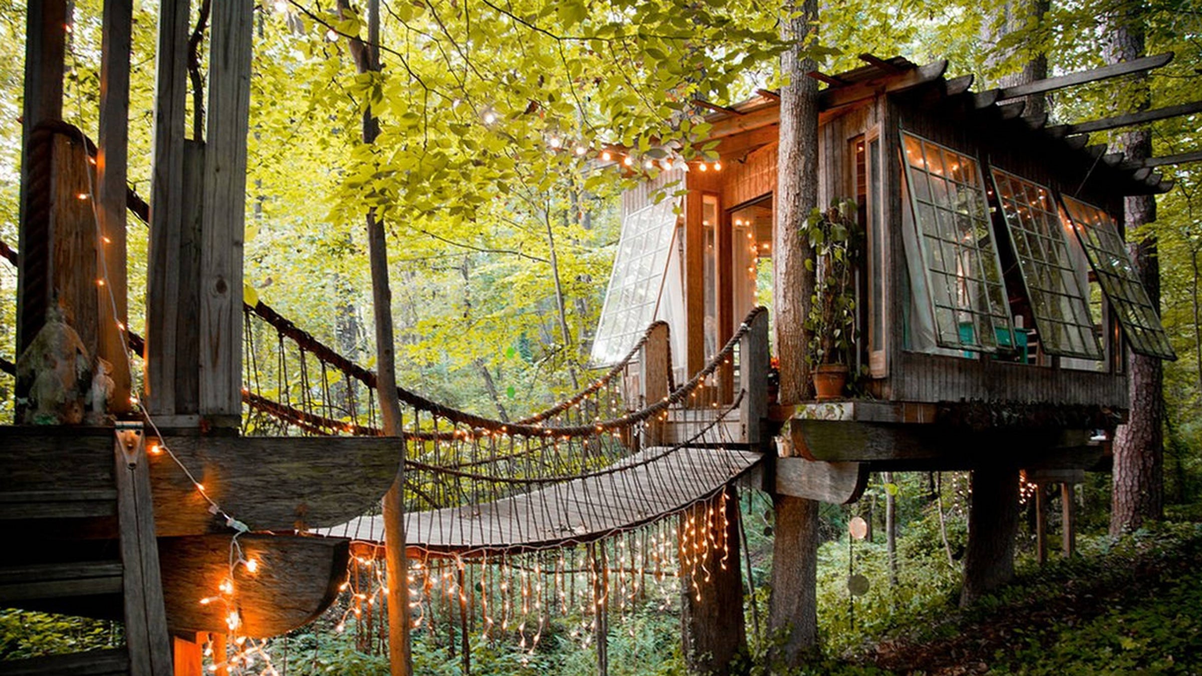 Suspension bridges connect three separate structures: a living room, bedroom, and deck.