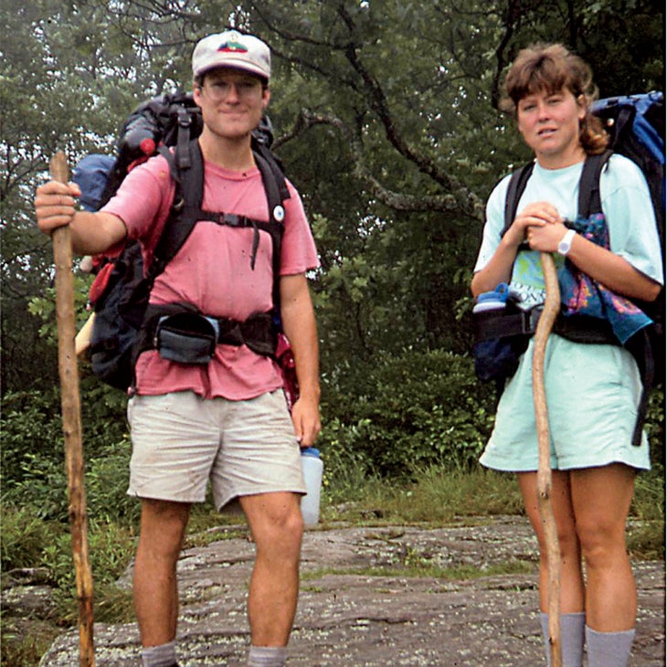 Biff and Cindi Bowen posing outside with hiking gear and a walking stick