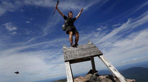A through-hiker celebrates on the top of a sign marking the northern terminus of the Appalachian Trail at the summit of Mt. Katahdin. Baxter officials say thru-hikers are openly using drugs and drinking alcohol, camping where they aren’t supposed to, and trying to pass their pets off as service dogs.