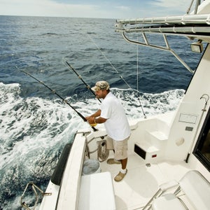 Young man getting fishing rods ready for a day of ocean big game fishing