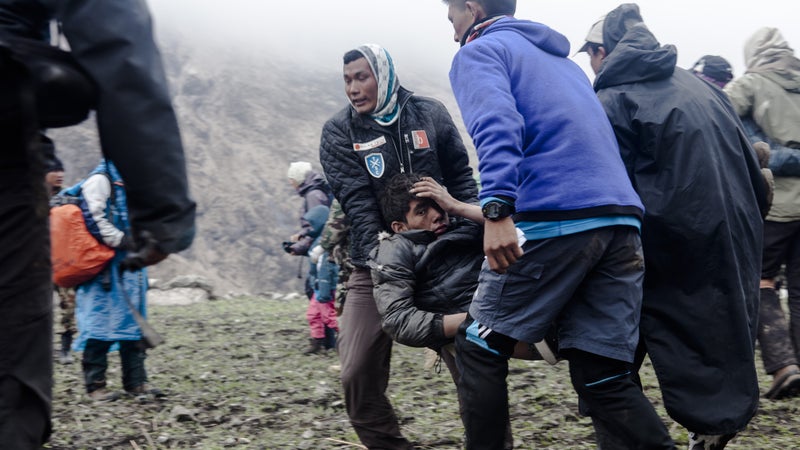 A group of Nepalese survivors rush their seriously injured friend to a waiting helicopter, hoping to get him one of the limited seats out of the valley on the day after the earthquake. Sunday, April 26, 2015.