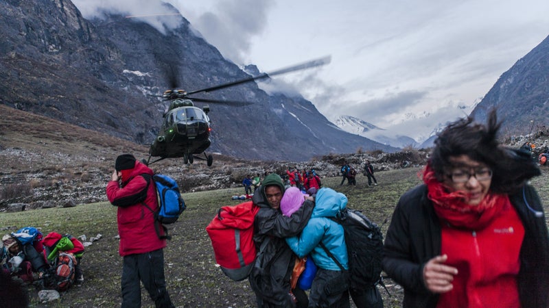 A group of survivors shield themselves against the powerful wind from a departing Nepalese Army helicopter. Monday, April 27, 2015.