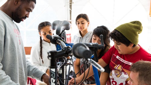 Players, volunteers from Optum, and kids from the 49ers Academy get down to business on one of the Raleigh bikes.