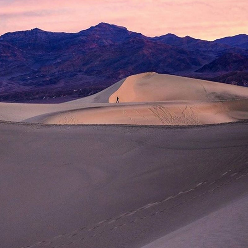A lone figure walks the Mesquite Flat Sand Dunes.