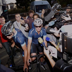 Lance Armstrong, center, rides through journalists while being surrounded by the media as he joins former England footballer Geoff Thomas and his team of ten amateur riders for two stages of the