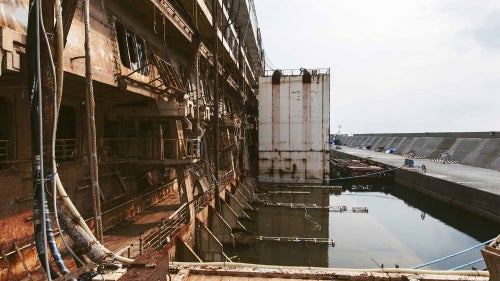 The wreck of the Costa Concordia is now moored in a floating dock; the entire right side of the ship is ripped open.