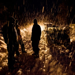 Skiers at night in a snow storm returning  from a day of snowcat skiing in the Mustang Powder Cats ski mountain area, BC, Canada.