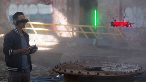 Drones race through neon-lit gates and up staircases doing 80 mph.