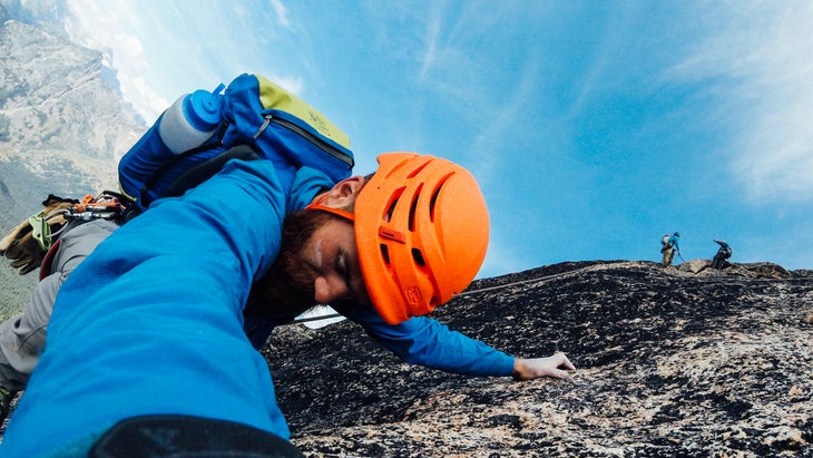 man in orange helmet and blue jacket climbing close-up