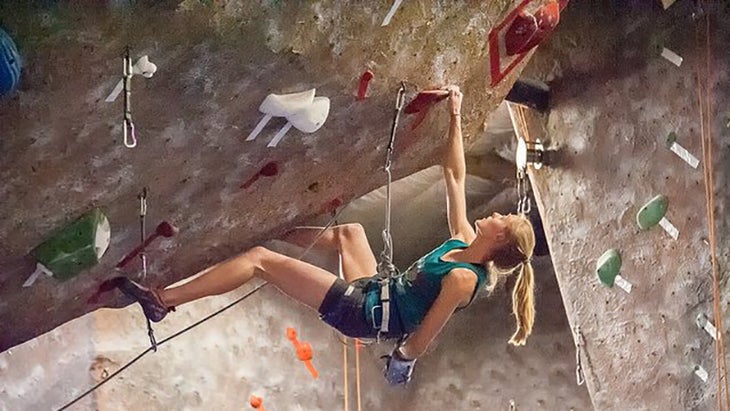 woman hanging onto a jug at the gym