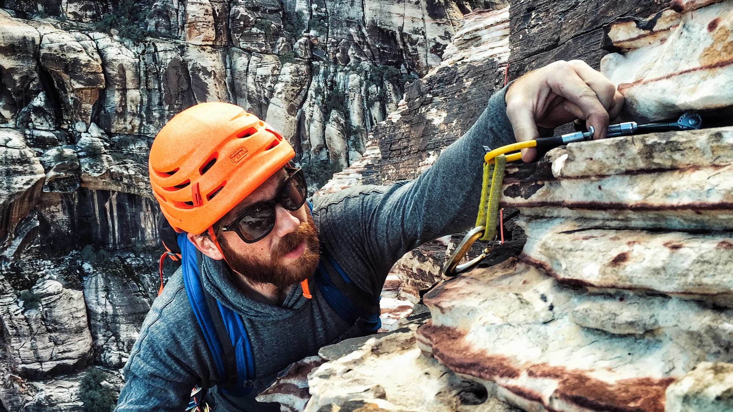 climber in orange helmet places protection outdoors