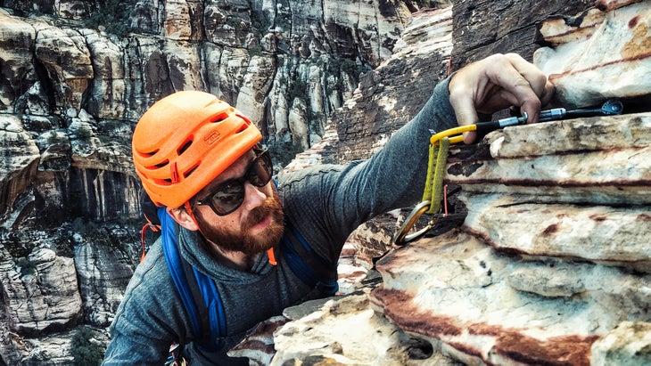 climber in orange helmet places protection outdoors