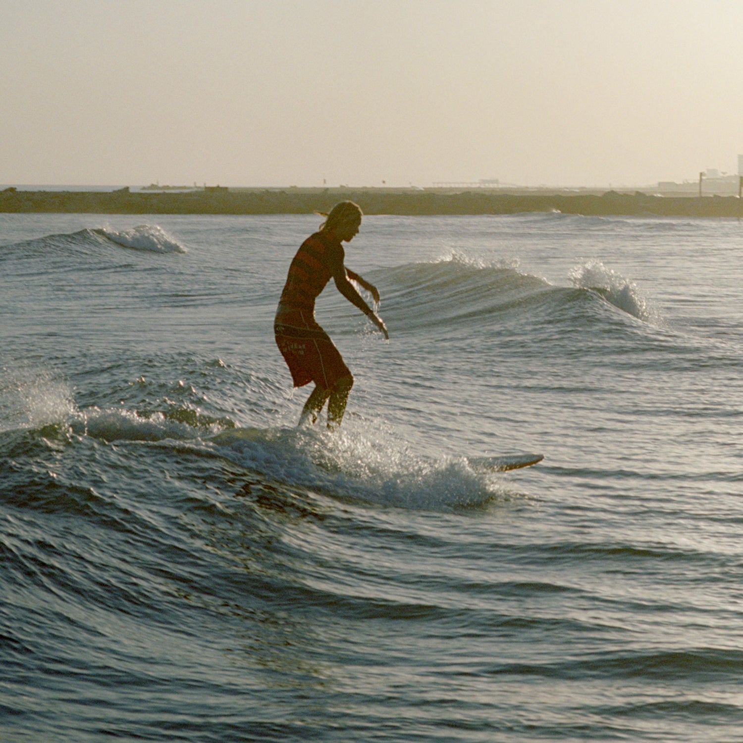 A teen age surfer catches a wave in the gulf of Mexico during a winter sunset. Galveston, Texas. America.