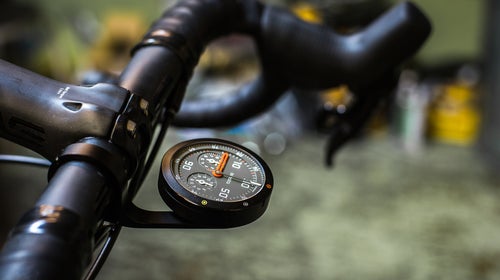 The Omata One displays speed, distance, vert, and time on a classic analog face.