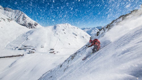 Enticed by soft snow, we skied a few lines before we summited. The train stop on Oberalp Pass is visible below skier John Trousdale.