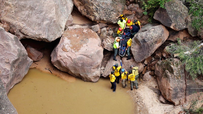 Rescuers pull a body from Pine Creek after the flash floods.