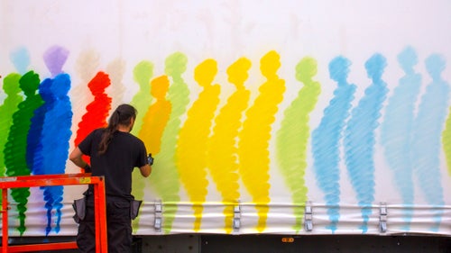The artist known as Suso33 works on one side of his truck. Since he has experience painting larger murals and backdrops for operas, Suso33 was comfortable with the massive scale of the canvases on the truck.