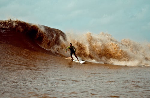 Surfer Michelangelo Bernardoni on the Pororoca Araguari River. The Pororoca, located in Brazil near the Amazon River, is a tidal bore that can reach heights of about 13 feet.