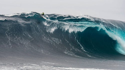 A lone surfer dances across the edge of a towering wall of water at Pedra Branca, Tasmania.