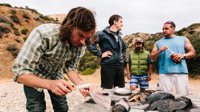 John fillets freshly speared fish for the tacos while Wes, Daniel, and Jeff look on.