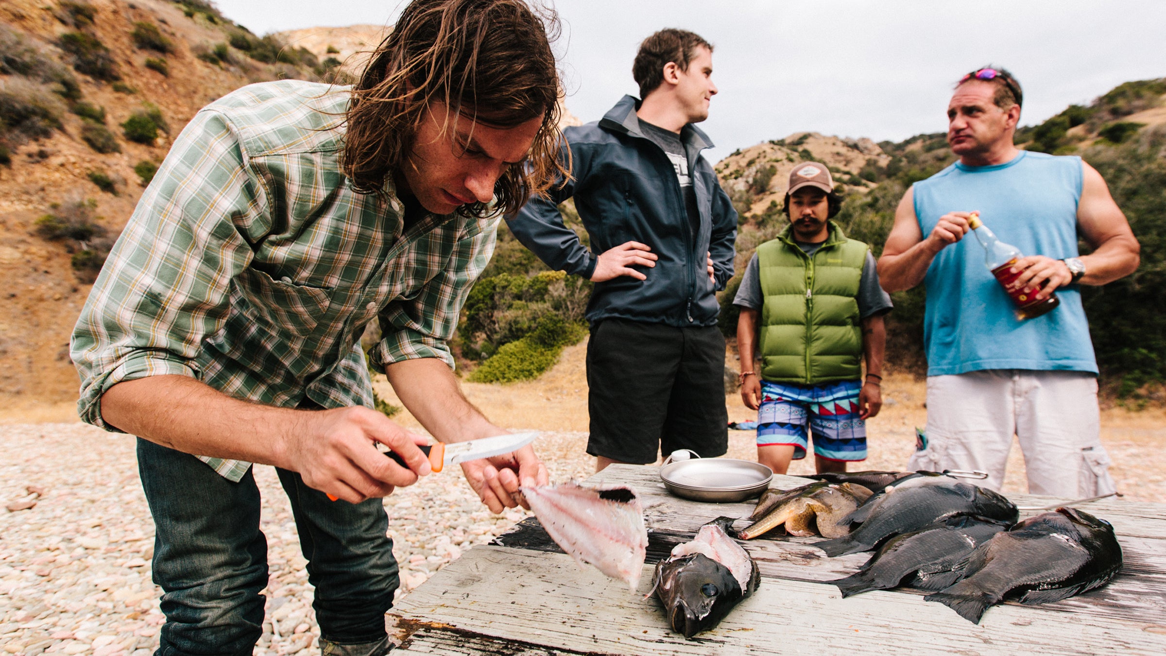 John fillets freshly speared fish for the tacos while Wes, Daniel, and Jeff look on.
