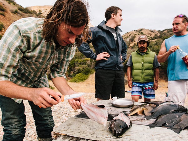 John fillets freshly speared fish for the tacos while Wes, Daniel, and Jeff look on.