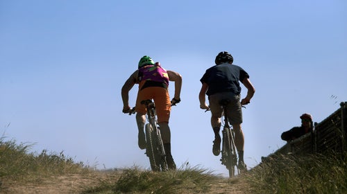 Two riders cruise up a hill during Sea Otter's e-MTB race.