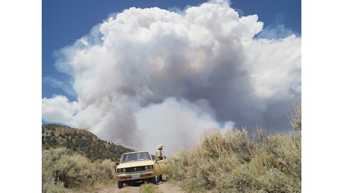 George chasing wildfires; Eureka, Nevada, 2012.
I met George in Diamond Valley, Nevada. He raised cattle for most of his life, but in his retirement, George enjoys chasing forest fires. We drove on dirt roads with dust coming up through the floor of his truck, and then stopped at this hill with fire burning on the other side. He told me very confidently that he had safety provisions. I asked what kind. He said, 鈥淚 have two bottles of water, a Coke, a candy bar, a shovel, and a handgun.鈥
Wildfires remove underbrush and kill diseases and insects, sparking new growth and allowing established trees to grow stronger. But the frequency of wildfires and the length of the wildfire season have been increasing. Since 1960, only seven years have seen more than 8 million acres burned in the United States, according to National Interagency Fire Center records. All of those years were in the past decade.