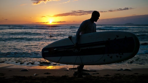 A surfer packs things up as the sun sets in Puerto Rico.