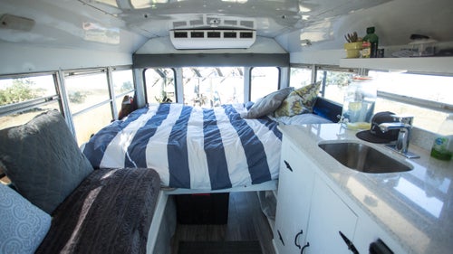 The bus came with seats, but Taylor pulled everything out, put in a laminate wood floor, sofa (with storage underneath), kitchen, and fold-out bed.