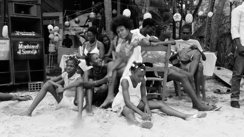 A group of girls watch the competition from the beach as concert speakers pump surf tunes spun by DJ Alain Maximilien, better known as
