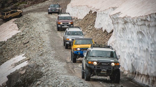 A line of FJ Cruisers and 4Runners make their way past mid-July snowbanks on the way up Imogene Pass.