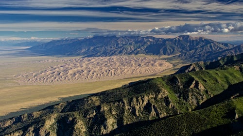 When I was young, I had a habit of poring through national park books, fantasizing about visiting them all. Now I’m a part-time aerial adventure photographer, and I’ve been able to fly my Piper PA-11 Cub Special plane over many of the places I used to daydream over.
 
In a few instances, I have made it a point to fly over a park. But many of my best national park shots happen on unplanned trips. While in pursuit of another item to photograph from the air, I happen to find myself flying through one of the national parks. Distraction takes over and I forget about my initial project.

Since we’re celebrating the national parks centennial, these are some favorite shots that I’ve taken over the last four years. I like the aerial perspective as it’s a fast track to seeing the full magnitude of a park’s beauty. I continue to find unbelievable hidden places inside the park system from the air.  

Photo: On this particular morning in September 2015, I was hoping to photograph nine peaks over 14,000 feet (five of them are viewable on the horizon where the clouds touch the peaks). Approaching from the airport in Alamosa, Colorado, the entire scene was shadowed by the rising sun, and I was convinced the entire exercise was going to be a waste of time. As I rode the winds to gain altitude over the Sangre de Cristo Range foothills, attempting to get a good angle on four fourteeners behind me, this panorama opened up.