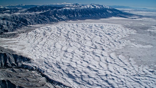 For those who visit Great Sand Dunes National Park in the summer tourist season with sand temperatures approaching 140 degrees, it鈥檚 hard to believe the place ever gets cold. The San Luis Valley of Colorado can indeed be one of the coldest areas of the country in winter, trapped in powerful inversions of cold air.
On this particular February afternoon, the dunes were covered in a layer of snow as I wore double layers of ski gear, sticking the camera out the window in temperatures of minus 20 degrees in pursuit of fourteeners on the horizon.
From the book 鈥淎bove the Summit: An Antique Airplane Conquers Colorado鈥檚 Fourteeners.鈥