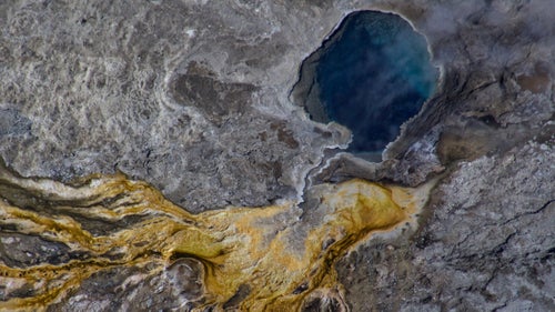 The most difficult photography of the national parks thus far has been the hot springs of Yellowstone. Their deepest secrets are visible directly overhead: The entire bacterial film from drainage paths as well as the core of the hot spring can be seen only from above. Attempting the same on the ground would result in edges of the spring crumbling, and serious injury or death from third-degree burns. The entire prospect is very challenging with a zoom lens, Yellowstone鈥檚 frequent turbulence, and an aircraft moving faster than a speeding car.