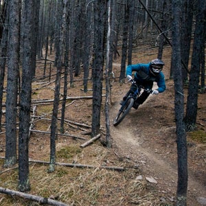 A male mountain biker rides a downhill bike trail in the forest.