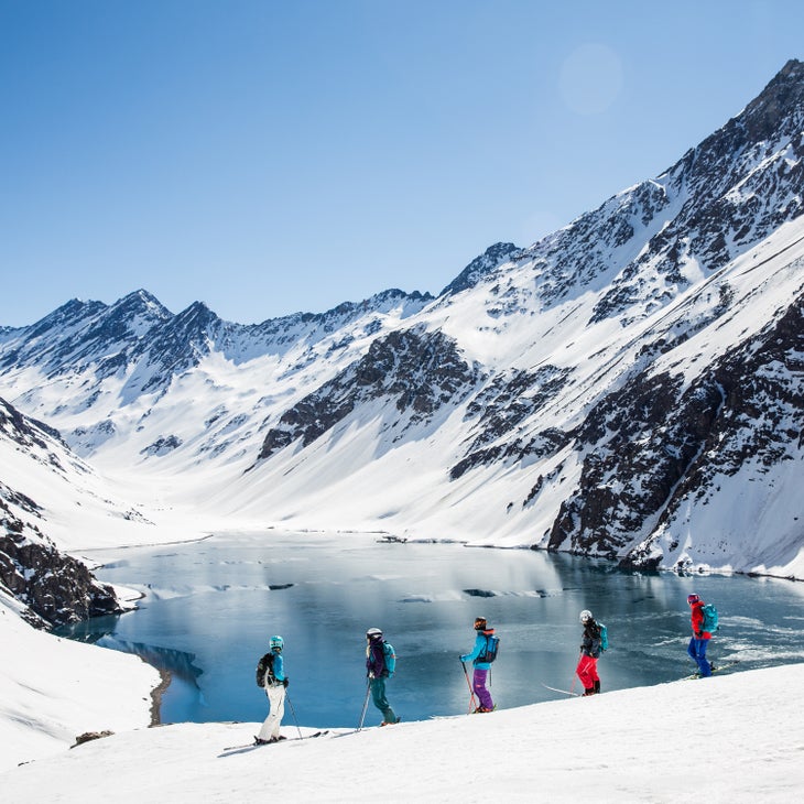 A group of skiers stop on the slope to admire Lago del Inca at Portillo, Chile.