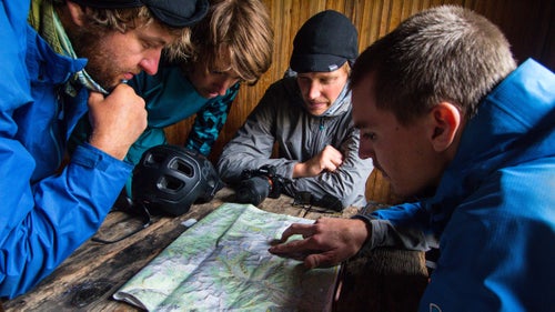 (Left to right) Kraushaar, Simmons, Stucki, and Trevor Downing take refuge from the monsoon weather in a small mining cabin. The crew studies the upcoming day’s routes, hoping for sun and hungry trout.