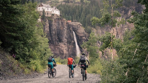 Spend ten days ripping singletrack and fly fishing through Colorado’s San Juan Mountains with a group of your best friends and you might just have a dream vacation. This August, photographer and rider Ben Kraushaar put together a crew of MTB and adventure junkies to do just that. With Telluride as the jumping off point, Kraushaar was joined by Justin Reiter, Dylan Stucki, Sam Simmons, and Trevor Downing for some high country trout, great riding, and plenty of challenging Colorado weather. Here, Kraushaar shares some favorite shots from their San Juan mission.
Photo: (Left to right) Sam Simmons, Justin Reiter, and Dylan Stucki pedal towards Bridal Veil Falls, the tallest waterfall in Colorado, in Telluride. We started our ten-day bikepacking trip in Telluride with the intention of fishing numerous alpine lakes and streams on our course through the San Juan Mountains.